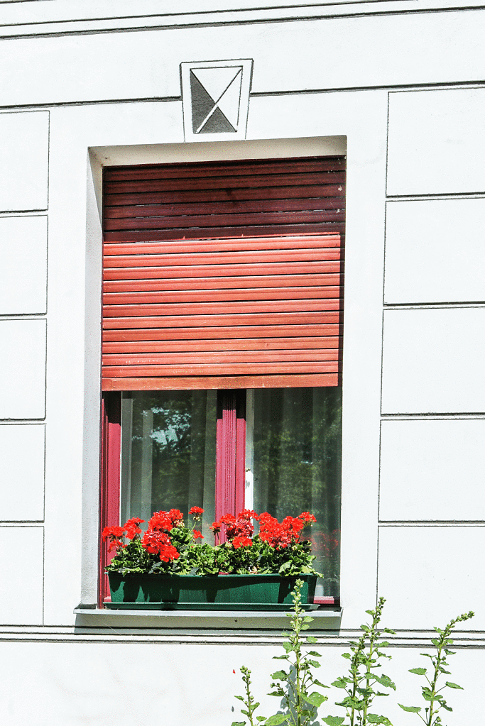 In Sgraffitotechnik  nachempfundene Stuckfassade um ein Fenster mit Holzjalousie.