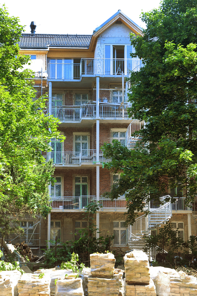 Hoffassade des Bestandsbaus mit vorgebauten Balkonen, Fluchtreppe und ausgebautem Dachgeschoss.